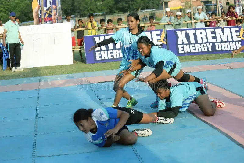 Pro Kabaddi League raider diving past defenders in intense mat tackle action